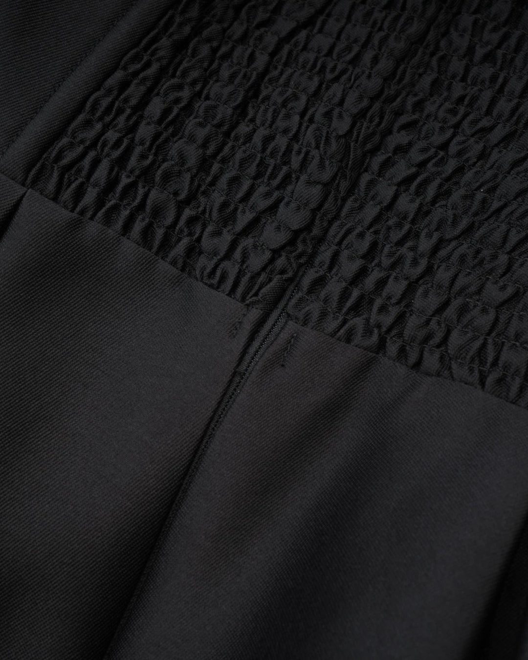 Close-up of a black dress with textured fabric and zipper detail of lydia casual midi dress