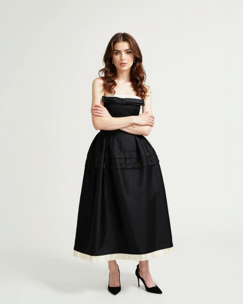 Woman wearing a black strapless midi dress with a white hem for a formal event