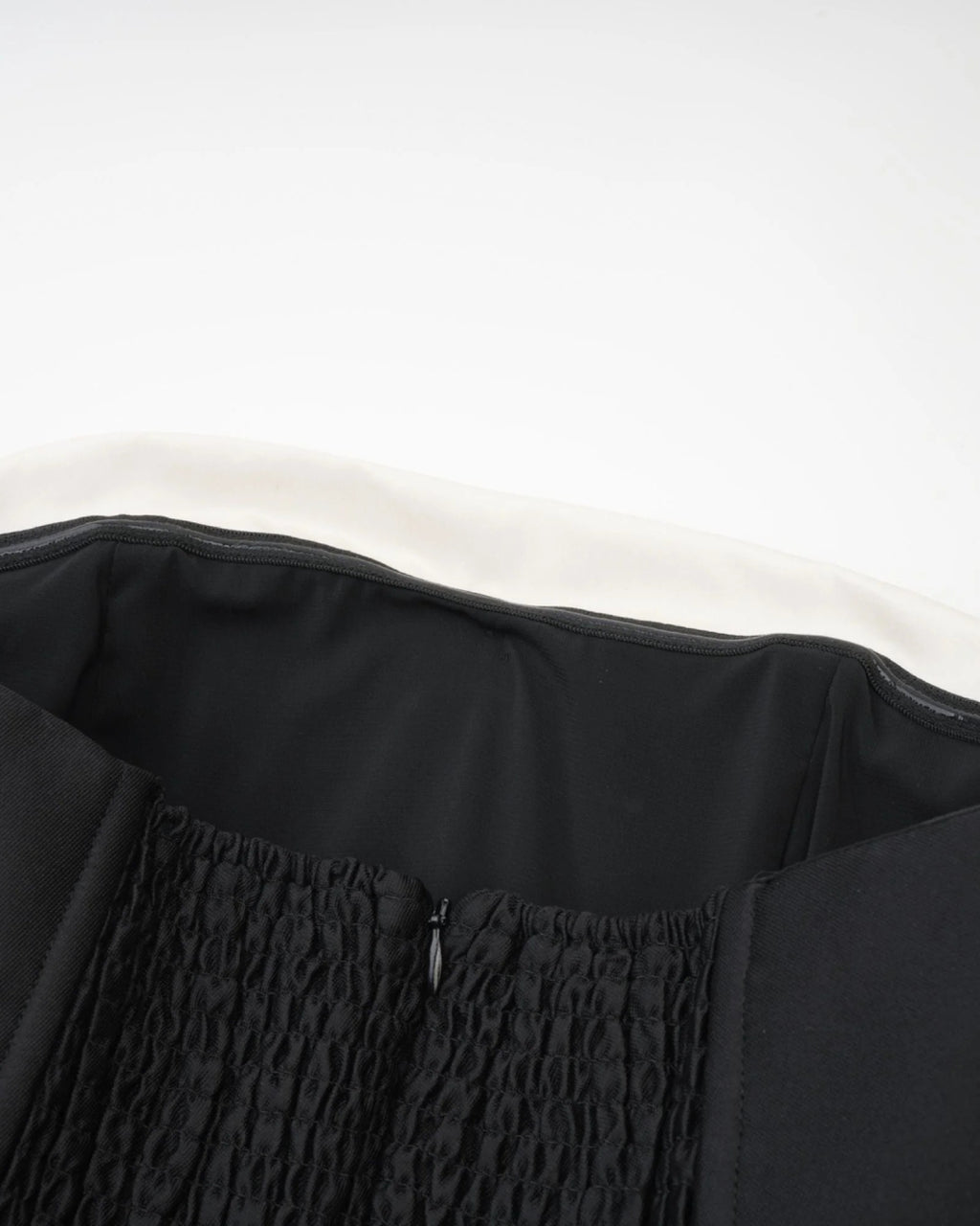 Close-up of a black garment with textured fabric and zipper of lydia midi dress in black