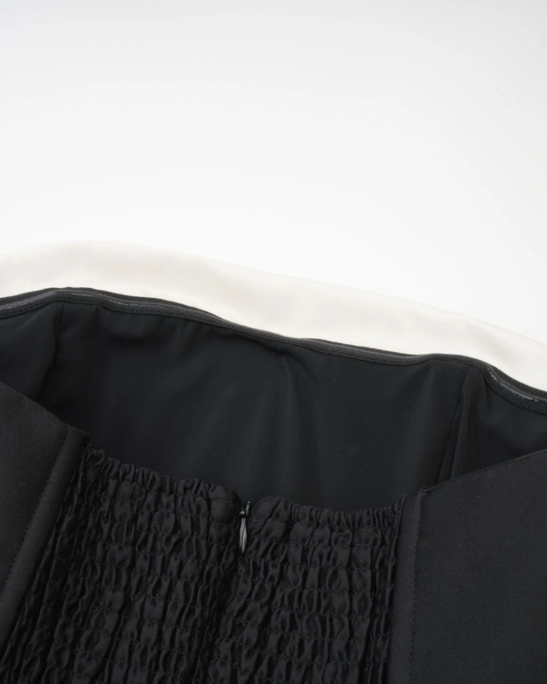 Close-up of a black garment with textured fabric and zipper of lydia midi dress in black